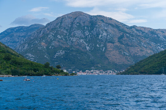 Kamenari, Montenegro - August 18, 2025: Wide panoramic landscape of the Bay of Kotor (Boka Kotorska) with dark blue sea water surrounded by steep green mountains under a cloudy sky