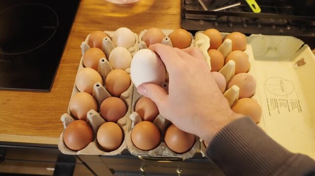 Person POV picking the huge egg among small eggs from the box
