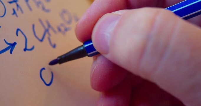 A close-up video of a marker writing a chemical formula on paper.