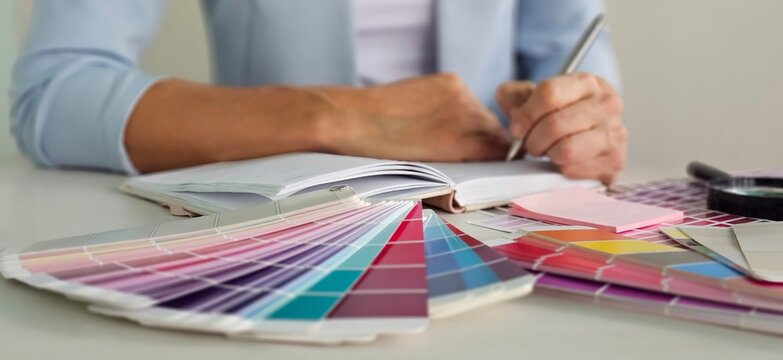 Interior architect designer at workstation table choosing various color samples art tool design with home blueprint