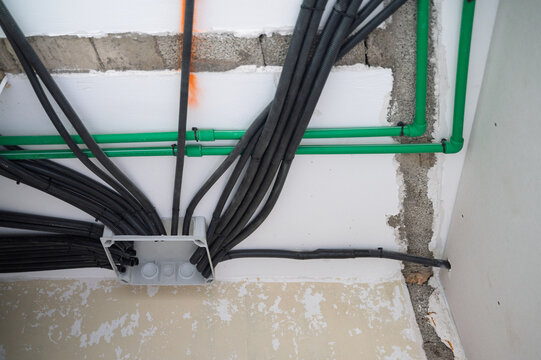 Electrical wiring and plumbing pipes installation in wall during home renovation