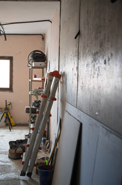 Home renovation interior with ladder, tools and unfinished wall during construction