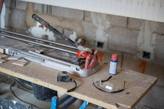 Manual tile cutter and tools on workbench during ceramic installation in construction site