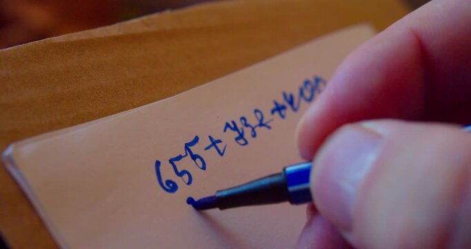 Close-up video of a marker writing numbers on a sheet of paper.