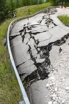 Broken road with cracks in the road surface, broken roadway of a mountain road, Belluno, Italy