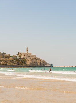 Surfers on the beach, Alma Beach, behind the old town of Jaffa with St. Peter's Church, old port, Tel Aviv-Jaffa, Israel