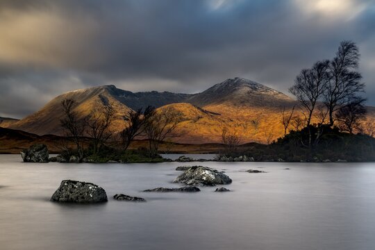 River Ba with mountain peaks of Meall a&acute;Bh&uuml;iridh and Clach Leathad in the background and dramatic clouds, Glen Coe, Rannoch Moor, west Highlands, Scotland, United Kingdom