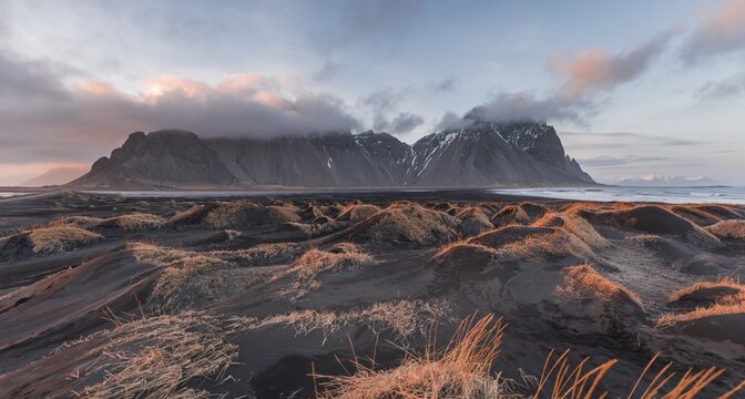 Evening atmosphere at the lava beach, black sandy beach with dunes, overgrown with dry grass, mountains Klifatindur, Eystrahorn and Kambhorn, headland Stokksnes, mountain range Klifatindur, Austurland, East Iceland, Iceland