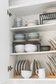 Open kitchen cabinet with neatly stacked dishes and bowls