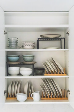Neatly organized kitchen cabinet with plates bowls and racks