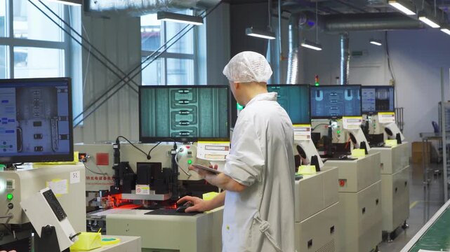 White engineer monitoring automation dashboards and display arrays, analyzing production data on multiple screens, performing process adjustments and system checks in electronics manufacturing bay