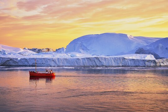 Red boat with tourists in front of icebergs in evening light, Icefjord, UNESCO World Heritage Site, Disko Bay, Ilulissat, West Greenland, Greenland