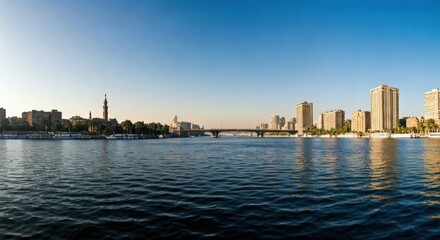 Obraz premium Panoramic cityscape of a river with buildings and bridge under a bright, clear sky