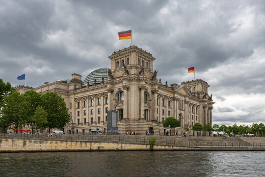 Reichstag with waving German flag at the Spree, government quarter, Berlin, Germany