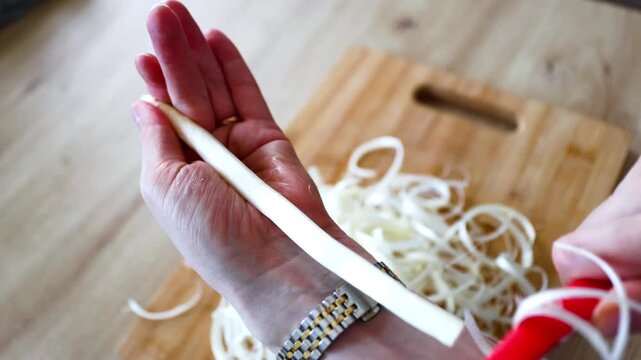 Human's hands pilling raw white asparagus on wooden background, close-up
