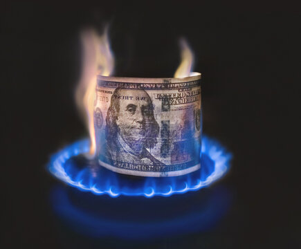Hundred dollar bill lit in flame of gas burner as concept of high natural gas prices and cost fuel.
