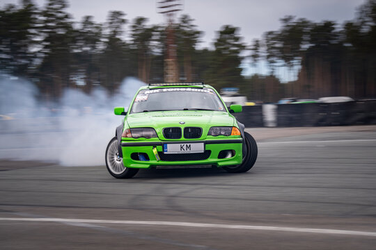 Riga, Latvia 2026-03-28  Green sports car drifting on racetrack with tire smoke