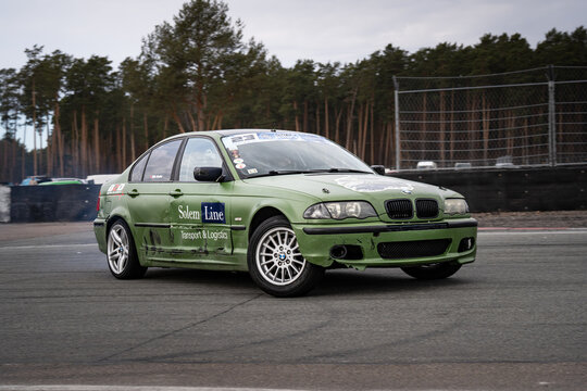 Riga, Latvia 2026-03-28  Green racing car on a track surrounded by trees