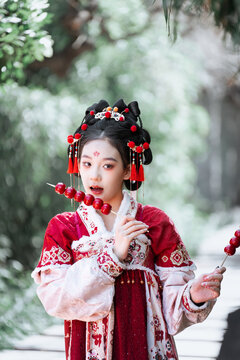 The girl in hanfu holds Tomatoes on sticks