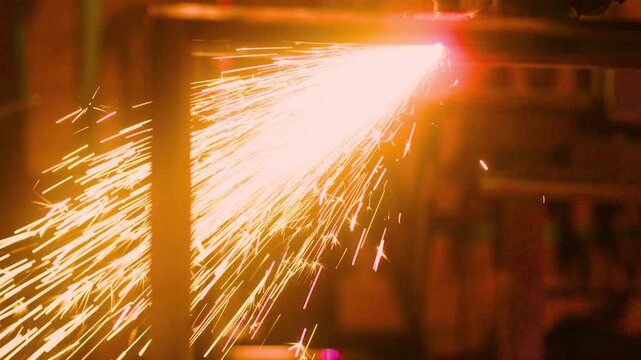 Industrial laser machine cutting metal frame with bright fire sparks.