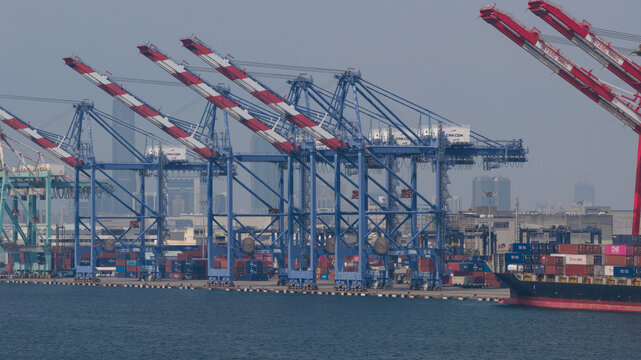 Fengsen Village, Taiwan - 26 February 2026: Aerial view of the industrial port with massive gantry cranes, stacked shipping containers, and a container ship docked along the waterfront.