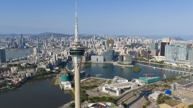 Macao - 16 February 2026: Aerial view of the Macau Tower and the urban skyline with Nam Van Lake and Ponte de Sai Van under a clear blue sky in Macao.