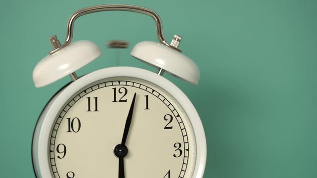 Classic white twin-bell alarm clock shaking and ringing loudly at six o'clock in the morning against a solid green background, representing a wake-up call, deadline, or the passage of time