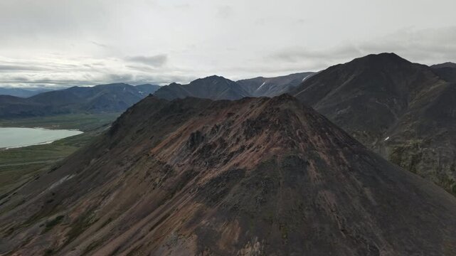 Aerial view captures a slow pan over a summit and glacier lakes. Provideniya, Chukotka, above Penkigney Bay near the Bering Strait. Cloudy late summer morning, cinematic travel scene