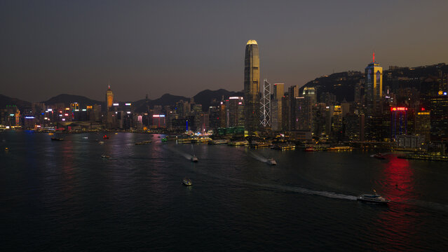 Hong Kong, Hong Kong - 13 February 2026: Aerial view of Victoria Harbour with illuminated skyscrapers, city lights reflecting on the water, and boats moving across the bay at night.