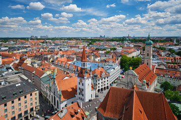 Obraz premium Elevated cityscape featuring the Altes Rathaus tower and the red roofs of the old town under a blue sky in Munich, Bavaria, Germany.