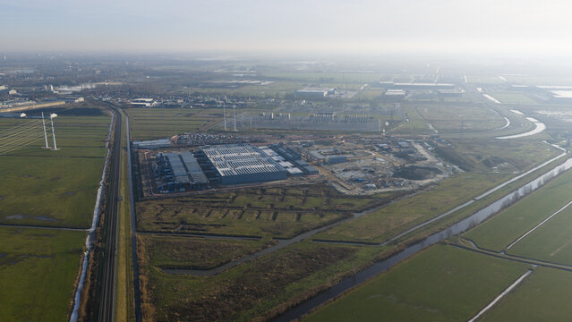 Groningen, Netherlands - 20 January 2026: Aerial view of Datacenter Westpoort with its large flat roof, surrounded by green polder landscape, canals, and a railway line under a hazy winter sky.