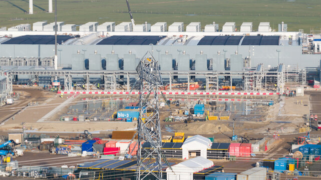 Groningen, Netherlands - 20 January 2026: Aerial view of Datacenter Westpoort under construction with solar panels on the roof and power pylons in the foreground.