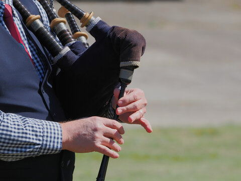 Man playing bagpipes in Scottish band marching at highland games. 