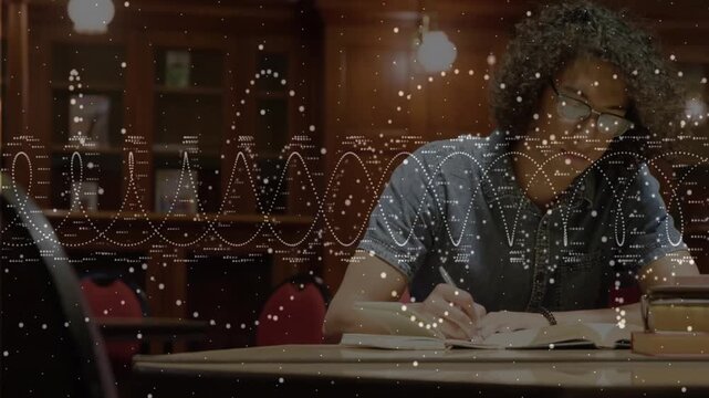 Male student writing notebook at library study area driving animated waveforms showing study focus