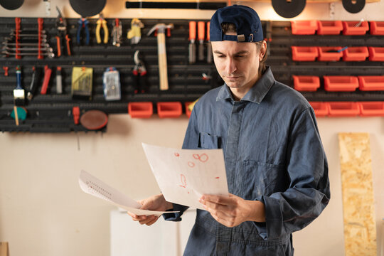 Carpenter man reading installation instruction paper for assembly furniture in carpentry shop