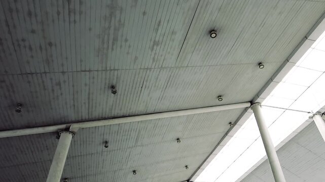 Modern industrial ceiling architecture with recessed lights and structural pillars background loop