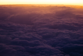 Fototapeta premium a high-altitude aerial view of a dense, fluffy cloudscape during a sunrise