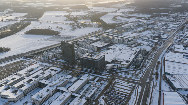 Veldhoven, Netherlands - 04 January 2026: Aerial view of ASML Building 7 and the surrounding high-tech campus covered in a layer of white snow under a soft winter light.