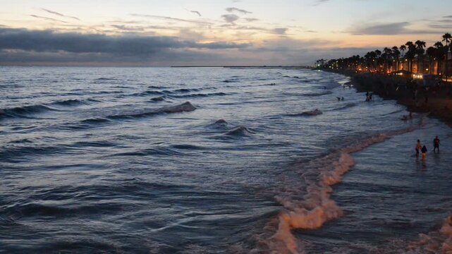 Waves slowly rolling onto a San Diego at sunset.