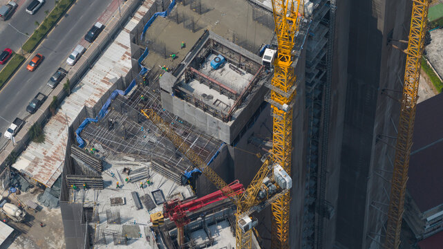 Pattaya, Thailand - 10 February 2026: Aerial view of Copacabana Coral Reef construction site, where yellow and red cranes stand tall amid concrete and steel, reflecting the sun's harsh rays.