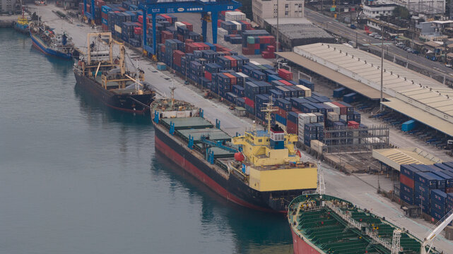 Keelung City, Taiwan - 20 February 2026: Aerial view of ships docked alongside a pier filled with neatly stacked, colorful containers, awaiting their next journey across the sea.