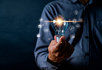 Businessman holding glowing light bulb with digital icons, representing innovation, creative idea, business strategy, problem solving, and smart technology solutions for digital transformation