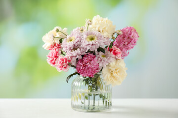 Naklejka premium Bouquet of beautiful flowers in vase on white table against blurred background