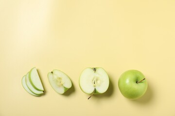 Naklejka premium Whole and cut fresh apples on pale yellow background, flat lay. Space for text