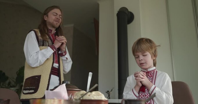 Man With Kid Boy Praying Before Dinner. Family in Ukrainian Traditional Attire Childhood. 4K 10-bit
