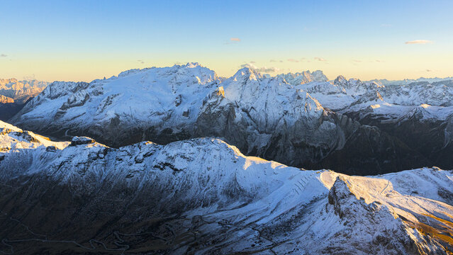 Aerial view of snow-dusted peaks piercing the crisp air, their jagged silhouettes a testament to nature's raw power, Marmolada, Dolomites, Italy.