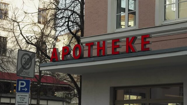 Pharmacy sign reading Apotheke on a building facade in Bogenhausen, Munich, Germany. Urban street scene with local healthcare service in a typical European residential district. Apotheke in Muenchen