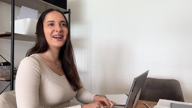Joven profesional riendo y mostrando brackets en momento distendido en la oficina