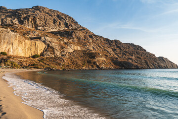 Fototapeta premium Waves crashing on the sandy beach in the bay between the hills