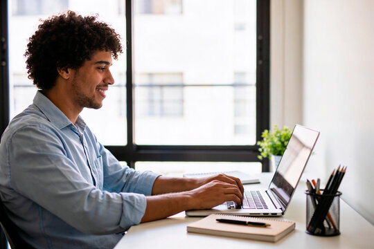 Homem trabalhando em home office com laptop em ambiente iluminado e organizado
